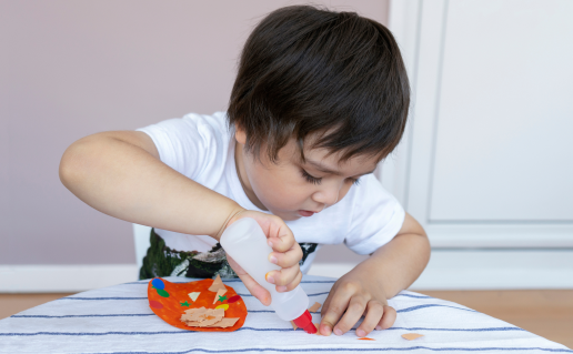 Toddler boy using glue