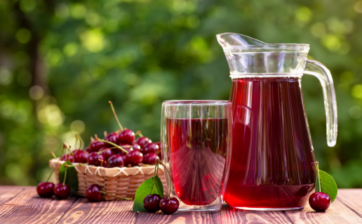 Dark red koolaid in glass pitcher and cup on outside table