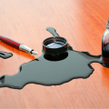 Spilled ink on wooden table next to half-full ink jar and fountain pen