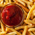 Small bowl of ketch amongst french fries